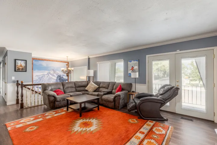 Living area featuring dark wood-style flooring, a mountain view, crown molding, a chandelier, and a textured ceiling