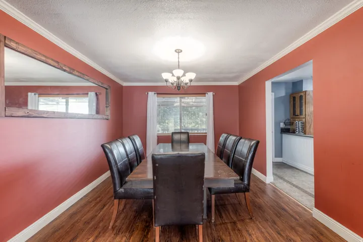 Dining space with dark wood-style flooring, a textured ceiling, a chandelier, and ornamental molding