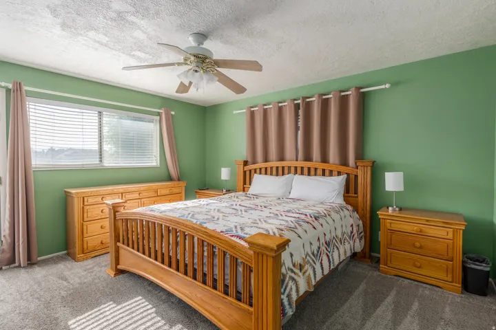 Carpeted bedroom with ceiling fan and a textured ceiling