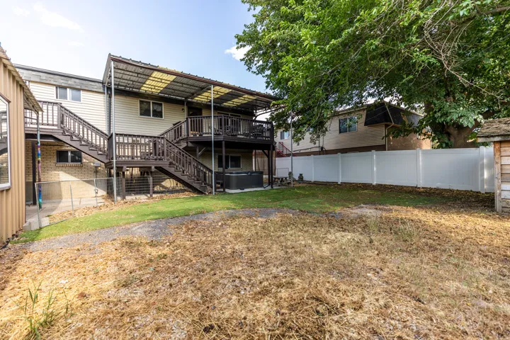 Back of house with a hot tub, stairs, a wooden deck, and a fenced backyard