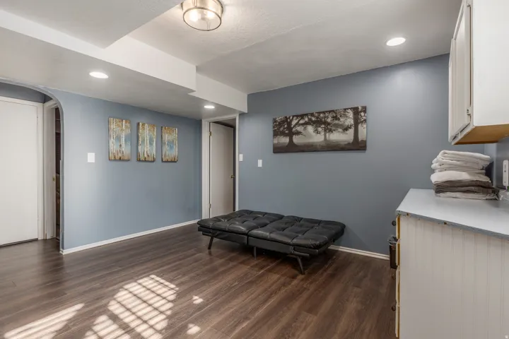 Living area with arched walkways, dark wood-style floors, and recessed lighting