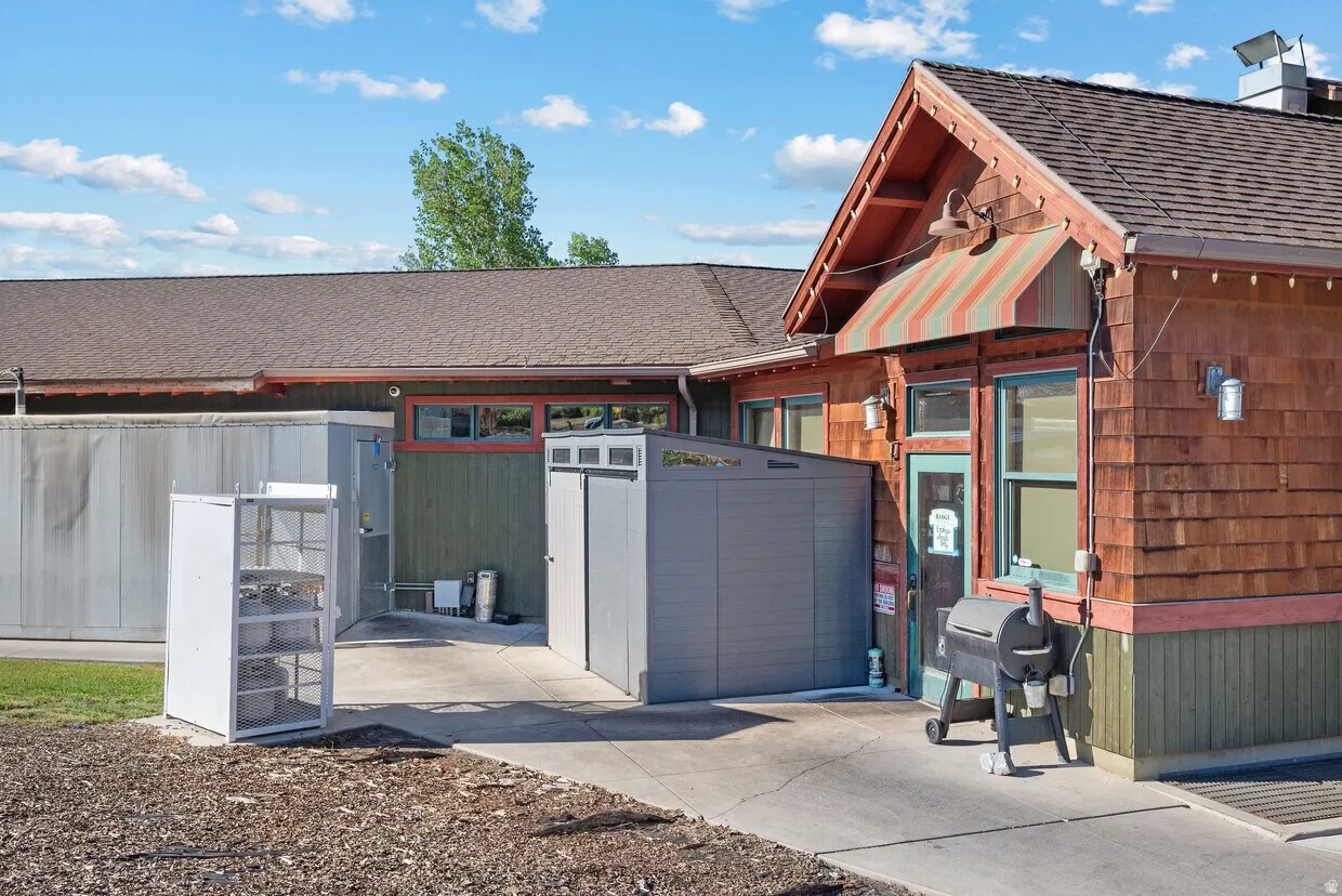Exterior space with a shingled roof and a storage unit