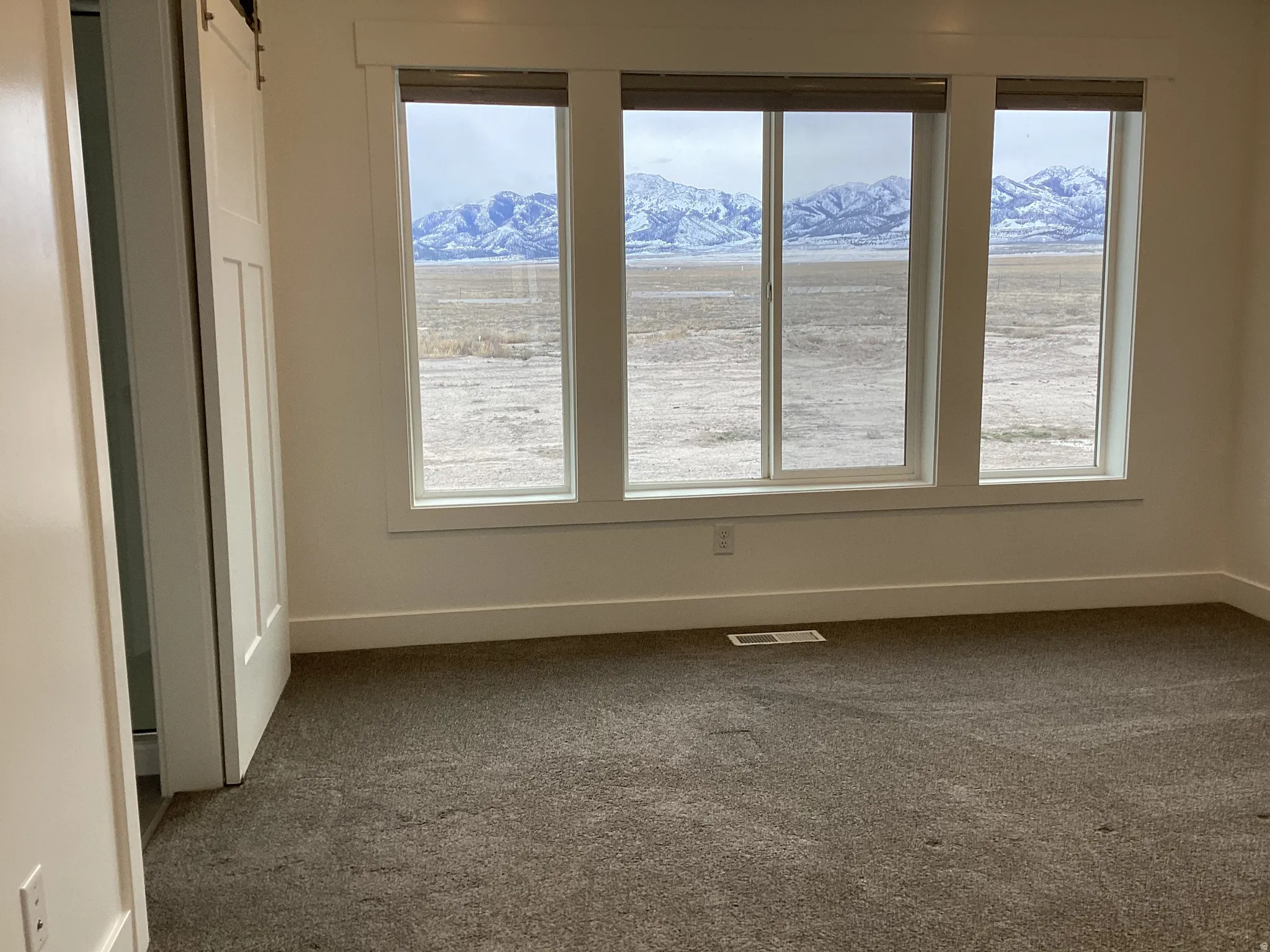 Spare room featuring dark carpet, a mountain view, and a barn door