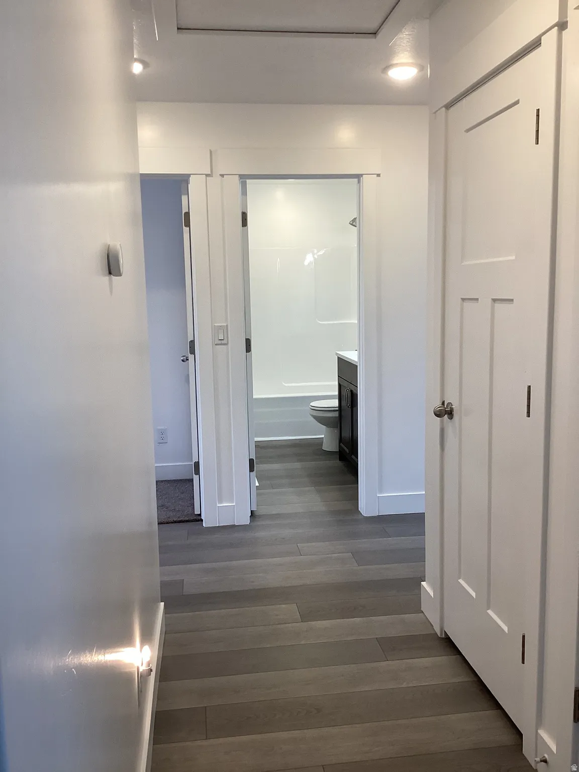 Hall with dark wood-type flooring and baseboards