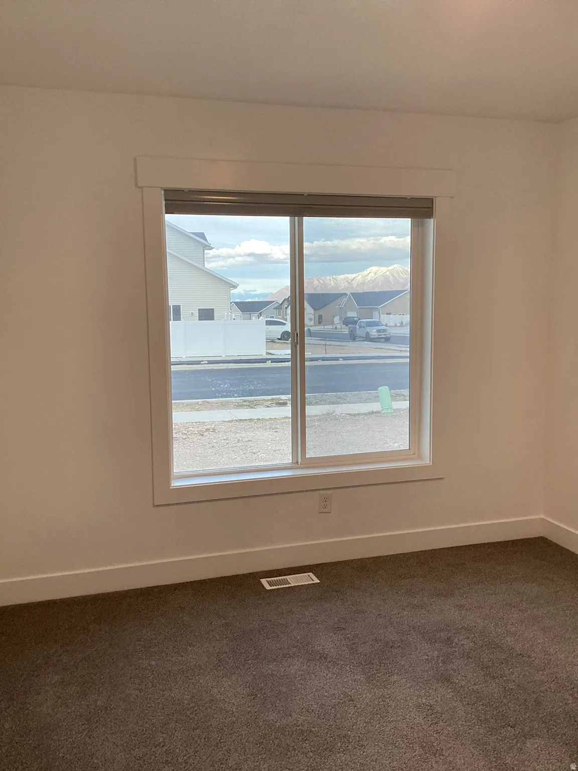 Spare room with dark colored carpet and a residential view