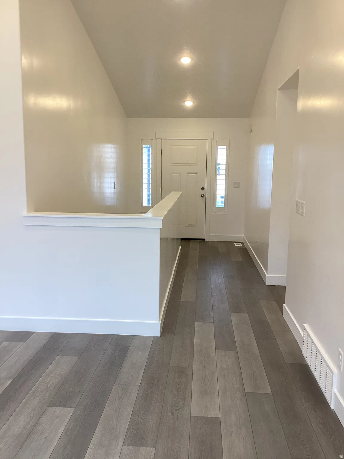 Entryway with dark wood finished floors, vaulted ceiling, and recessed lighting