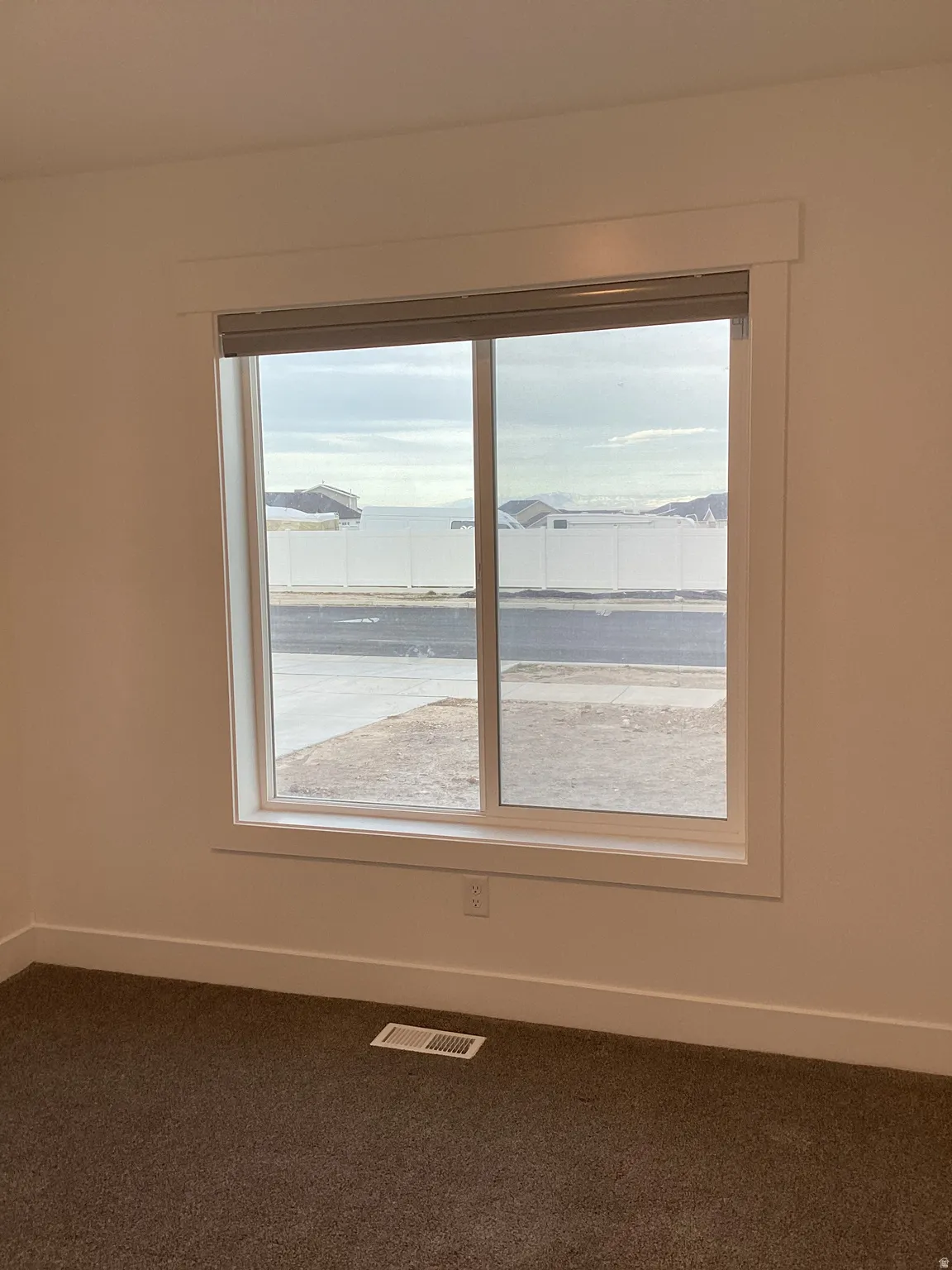 Empty room featuring baseboards and dark colored carpet