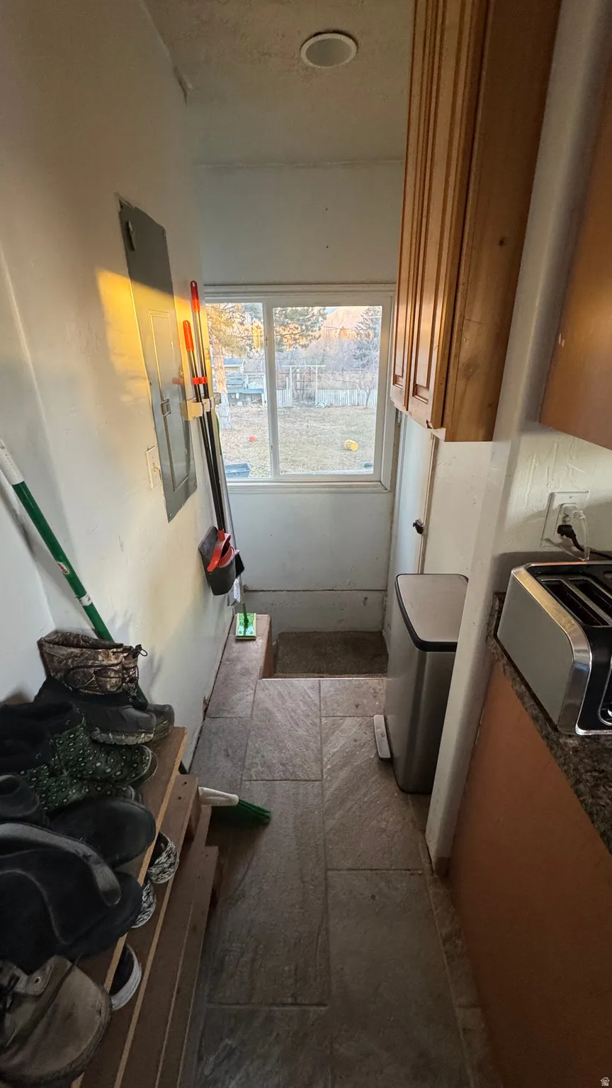 Kitchen with brown cabinets, electric panel, and dark stone countertops