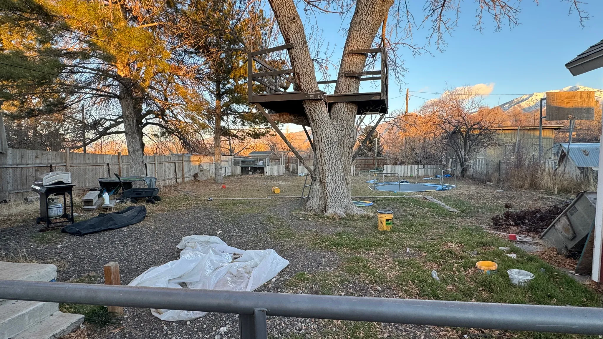 Fenced backyard with a trampoline and a patio area