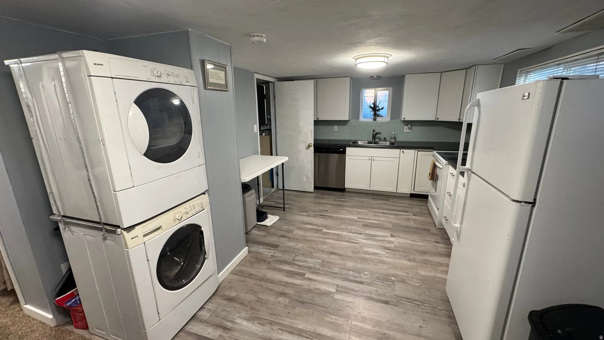 Laundry area with light wood finished floors and estacked washer and dryer