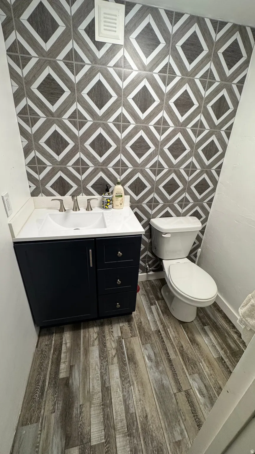 Half bathroom with vanity and dark wood-style floors