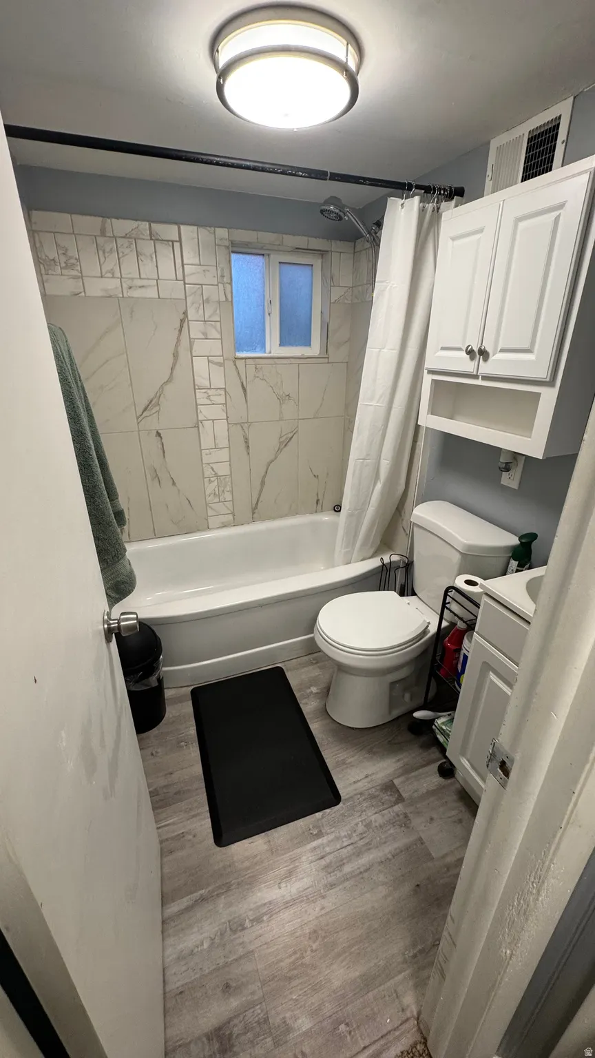 Full bathroom with shower / tub combo with curtain, vanity, and light wood-style floors
