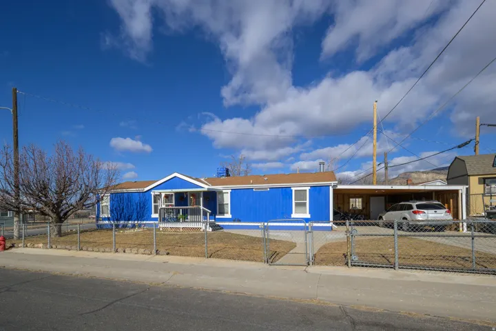Single story home featuring an attached carport, a gate, a fenced front yard, and driveway