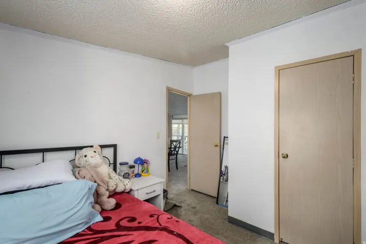Carpeted bedroom featuring a textured ceiling and crown molding
