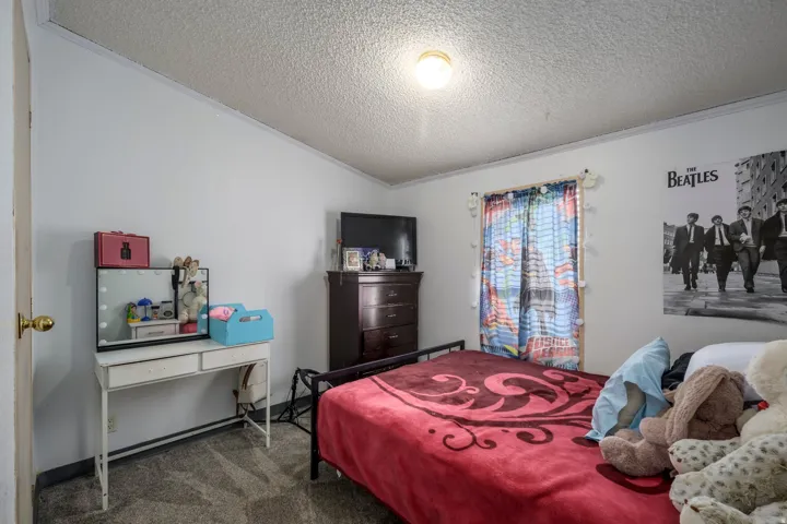 Carpeted bedroom with a textured ceiling and ornamental molding