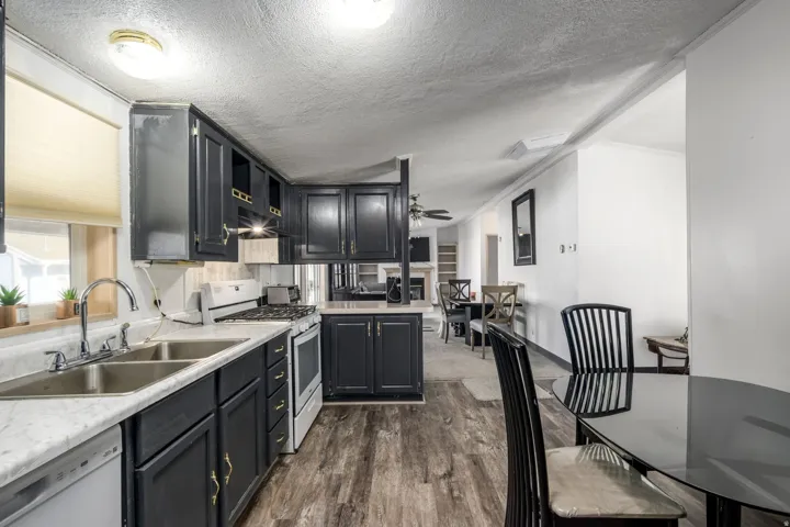 Kitchen with white appliances, light countertops, a textured ceiling, dark wood-style flooring, and a ceiling fan