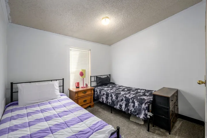 Bedroom featuring dark colored carpet, a textured ceiling, and crown molding