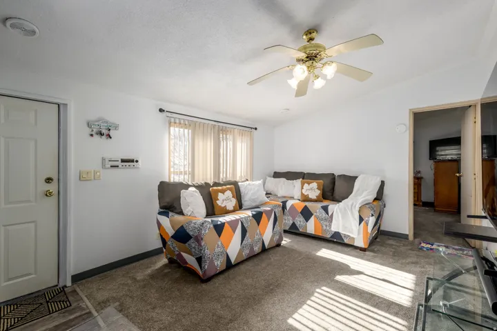 Carpeted living room with lofted ceiling, a ceiling fan, and a textured ceiling