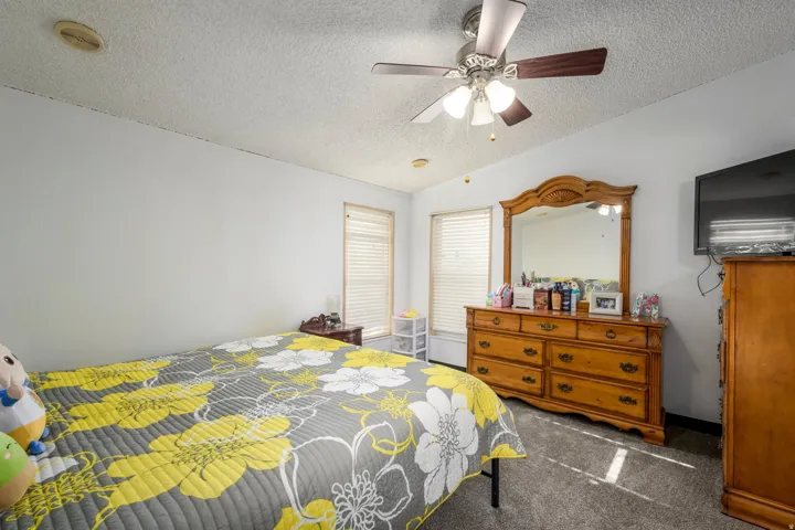 Bedroom featuring dark carpet, ceiling fan, and a textured ceiling