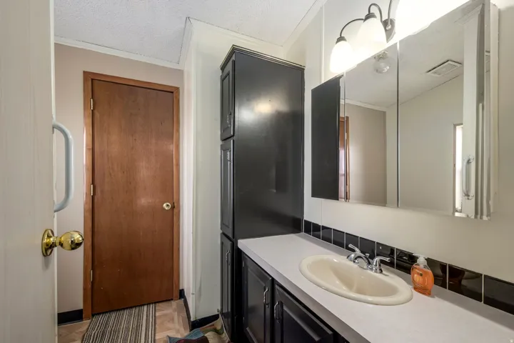 Bathroom featuring vanity, ornamental molding, parquet floors, and a textured ceiling