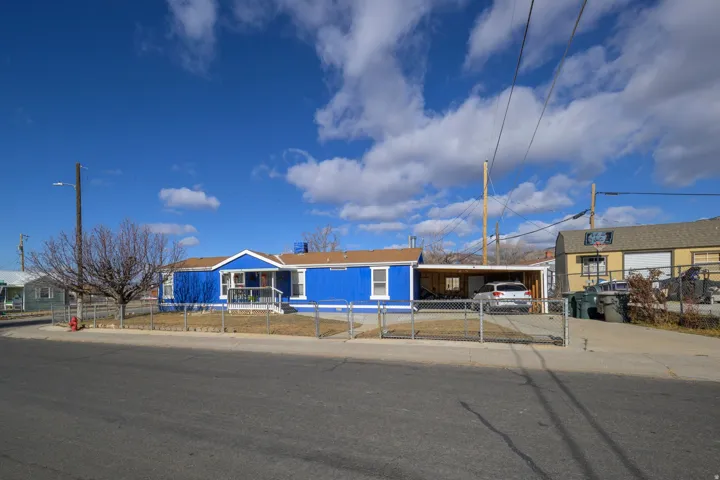 Single story home with a fenced front yard, an attached carport, a gate, and concrete driveway