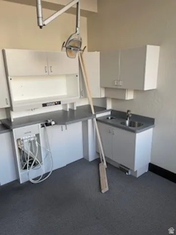 Kitchen featuring dark countertops, white cabinets, and dark carpet