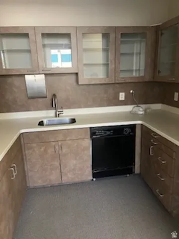 Kitchen featuring light countertops, dishwasher, and glass insert cabinets
