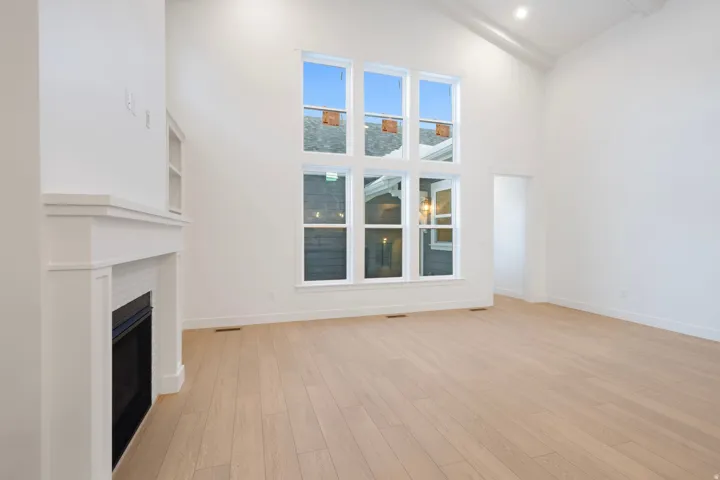 Unfurnished living room featuring a fireplace, light wood finished floors, high vaulted ceiling, and beamed ceiling