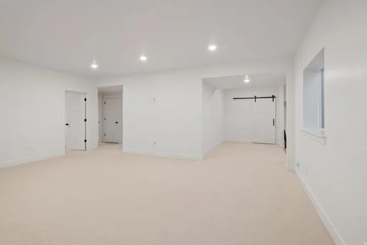 Spare room with a barn door, light carpet, and recessed lighting