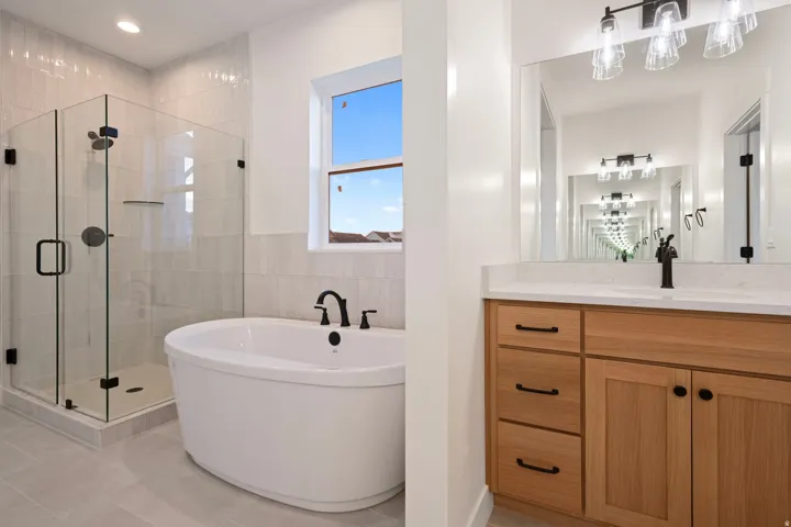 Full bathroom with a stall shower, a freestanding tub, vanity, tile walls, and light tile patterned floors