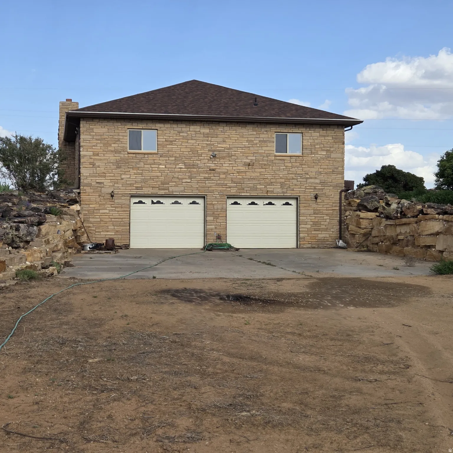 View of home's exterior with a garage, a chimney, concrete driveway, roof with shingles, and stone siding