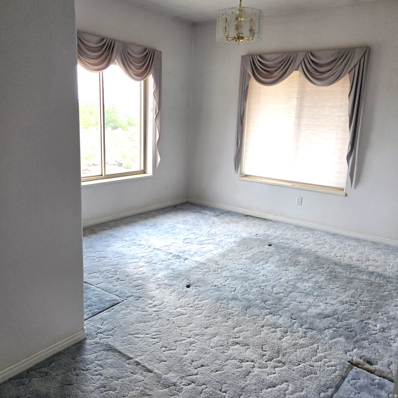 Spare room featuring a chandelier and carpet