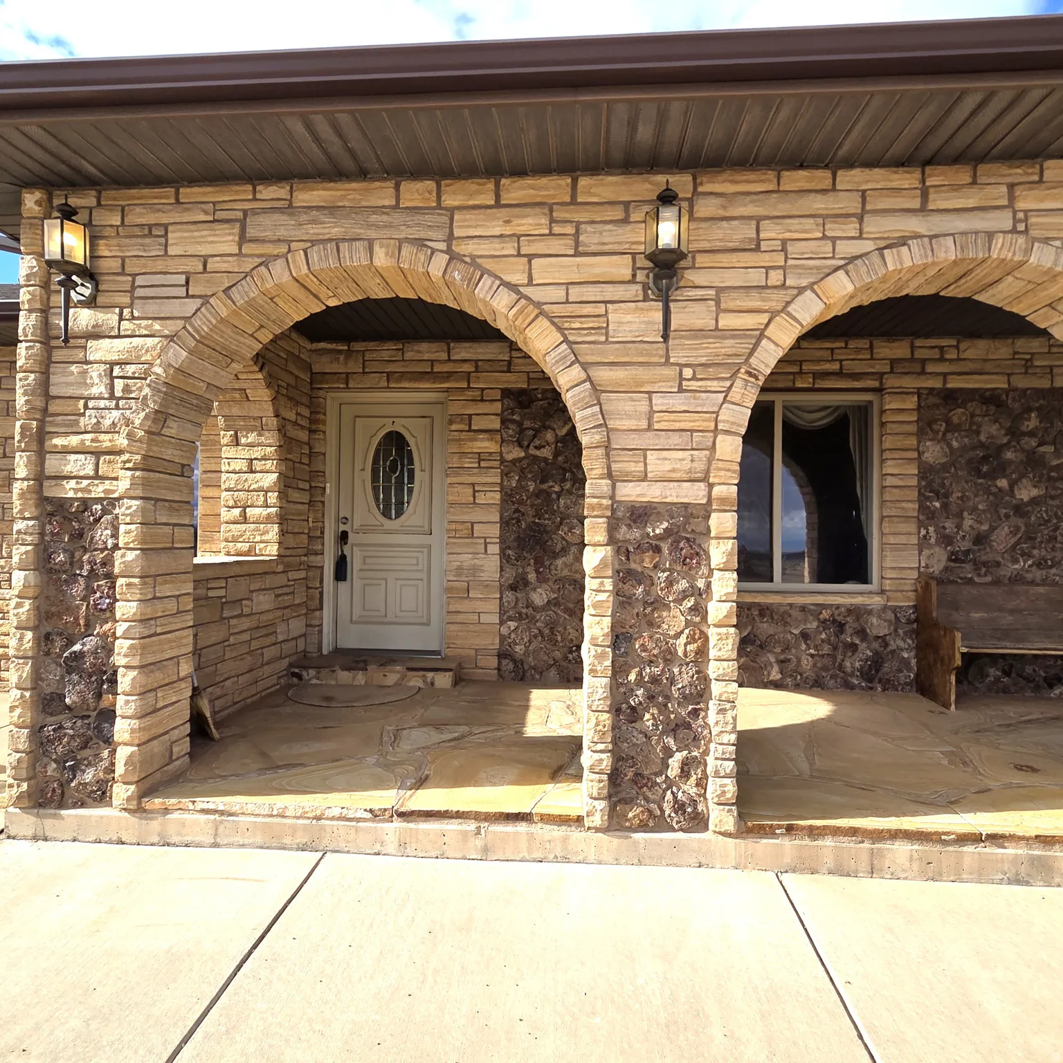 View of exterior entry featuring stone siding and a porch