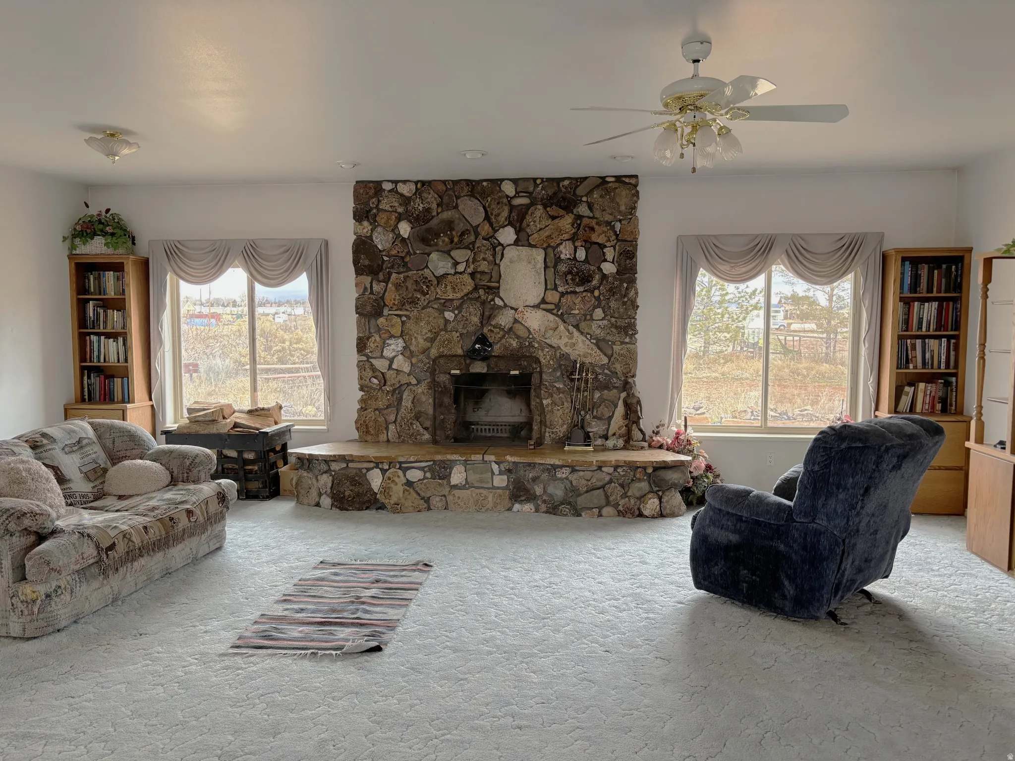 Carpeted living area with a fireplace and ceiling fan