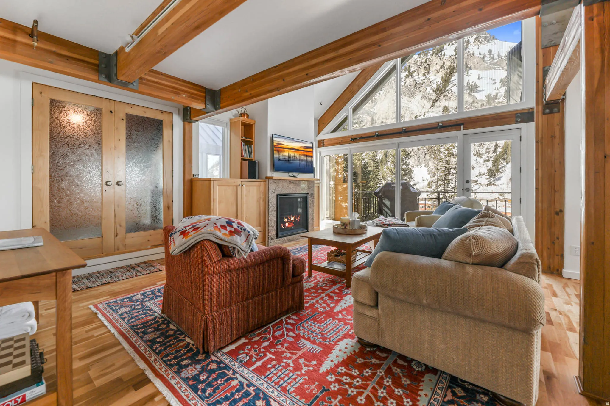 Living room with enclosed hot tub room, a fireplace with flush hearth, Georgeous Hardwood floors, and high vaulted beamed ceiling