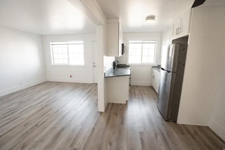 Kitchen with freestanding refrigerator, white cabinetry, light wood-type flooring, and open floor plan