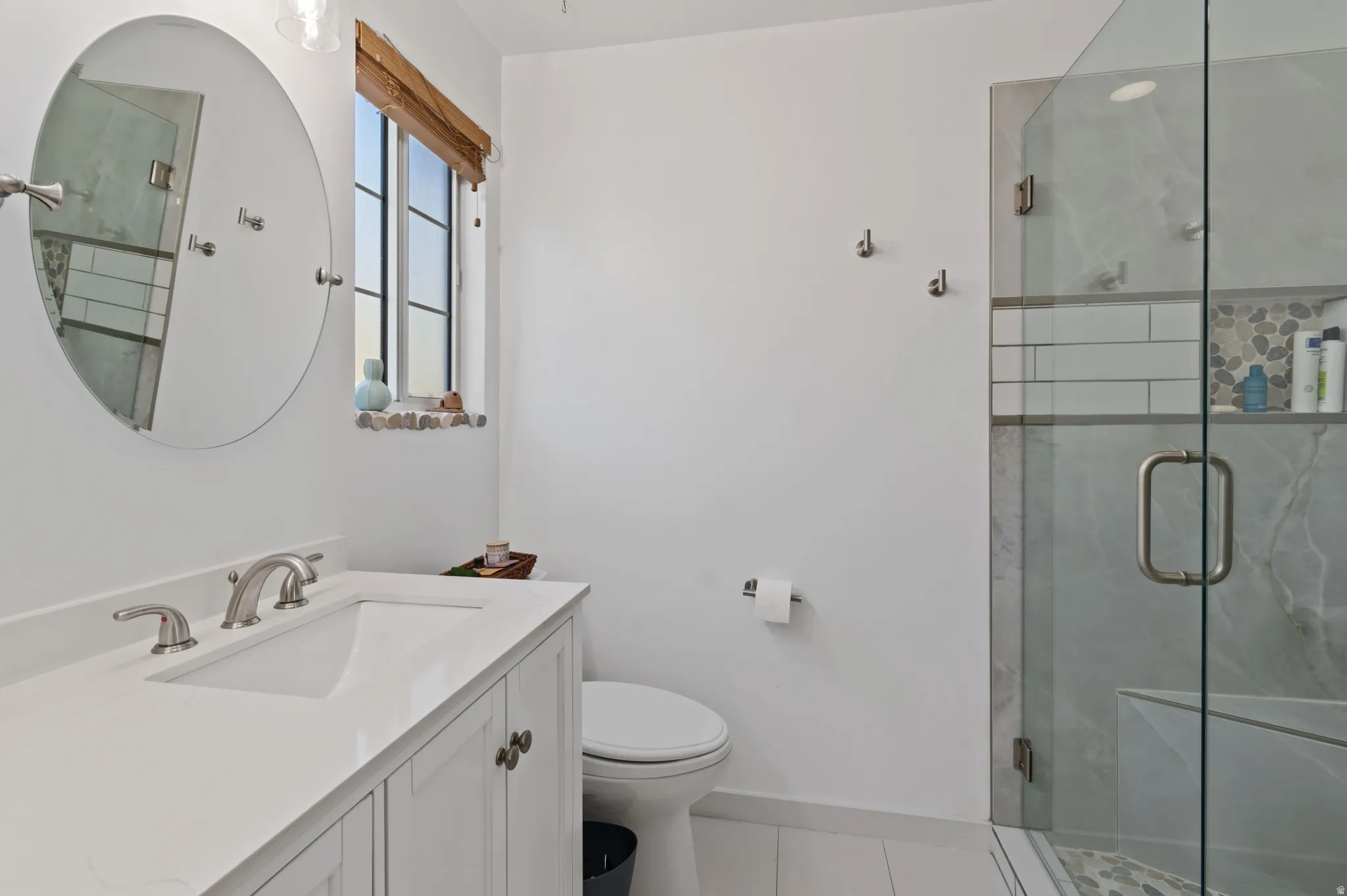 Full bath with a marble finish shower, vanity, and light tile patterned floors