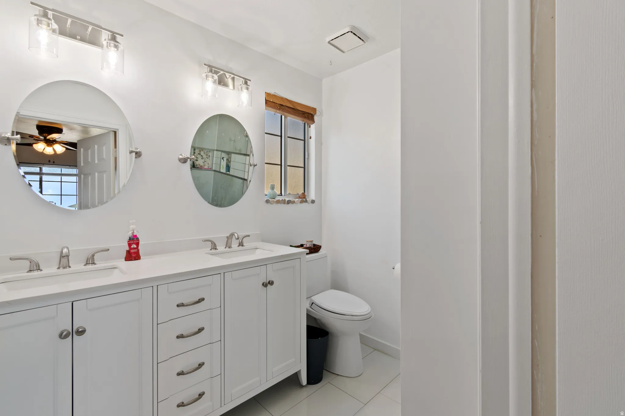 Bathroom featuring double vanity, a ceiling fan, and light tile patterned floors