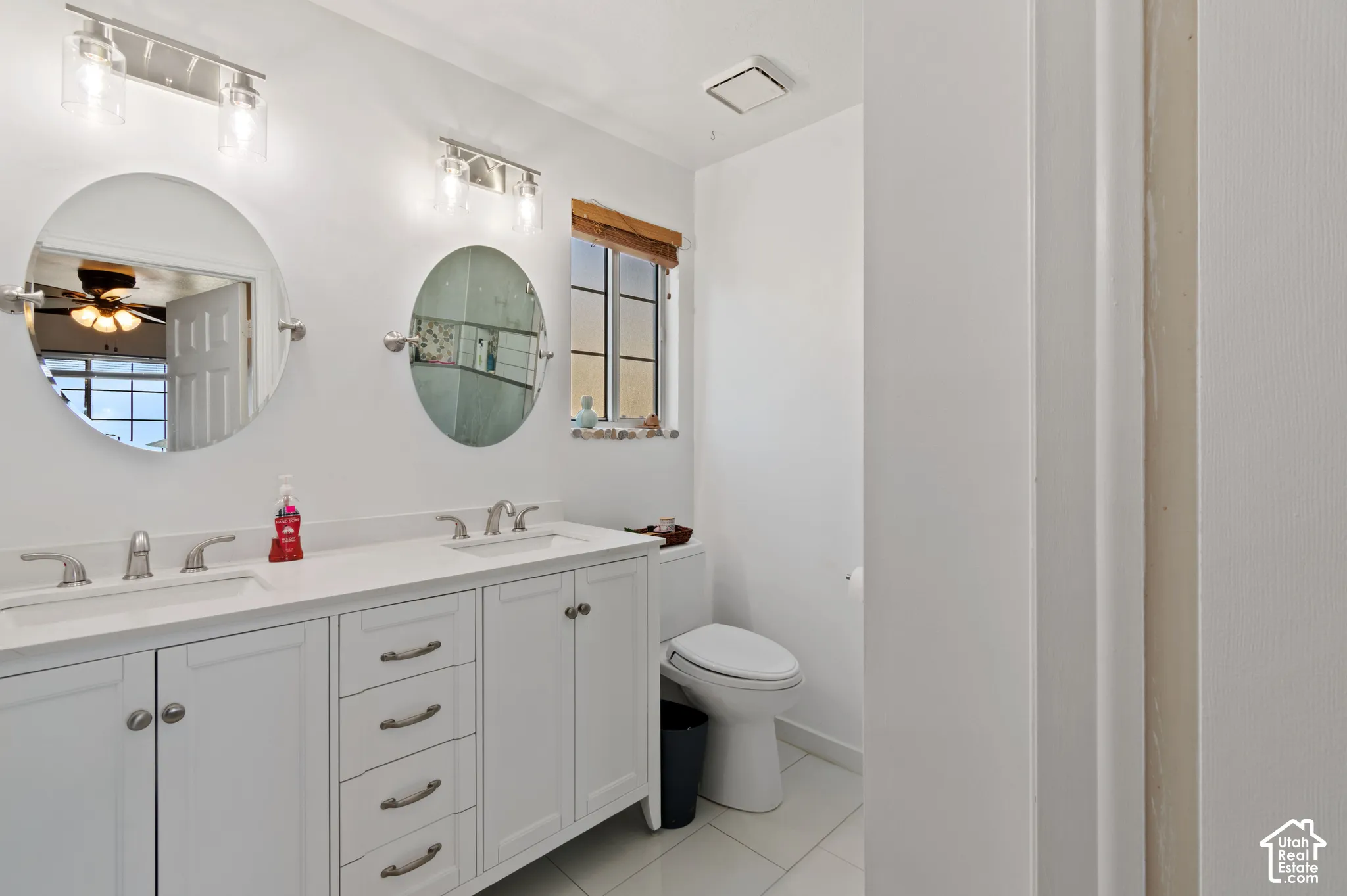 Bathroom featuring double vanity, a ceiling fan, and light tile patterned floors