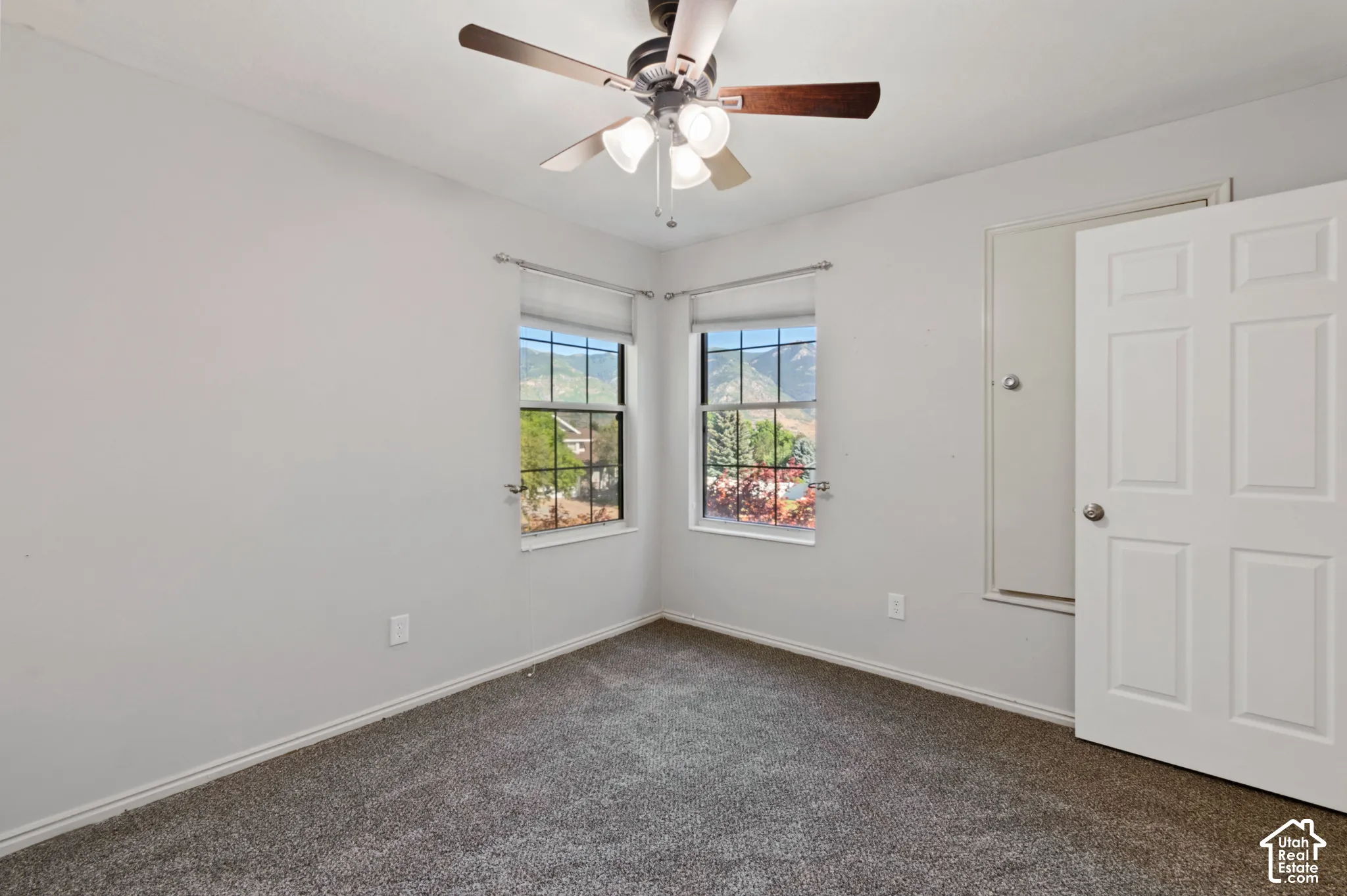 Empty room with dark carpet and ceiling fan