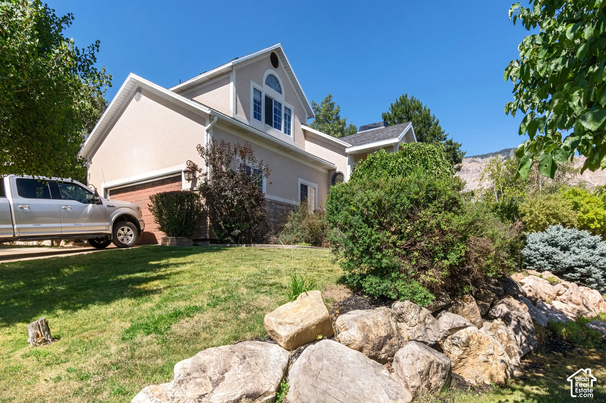 View of side of home with stucco siding, a lawn, and a garage