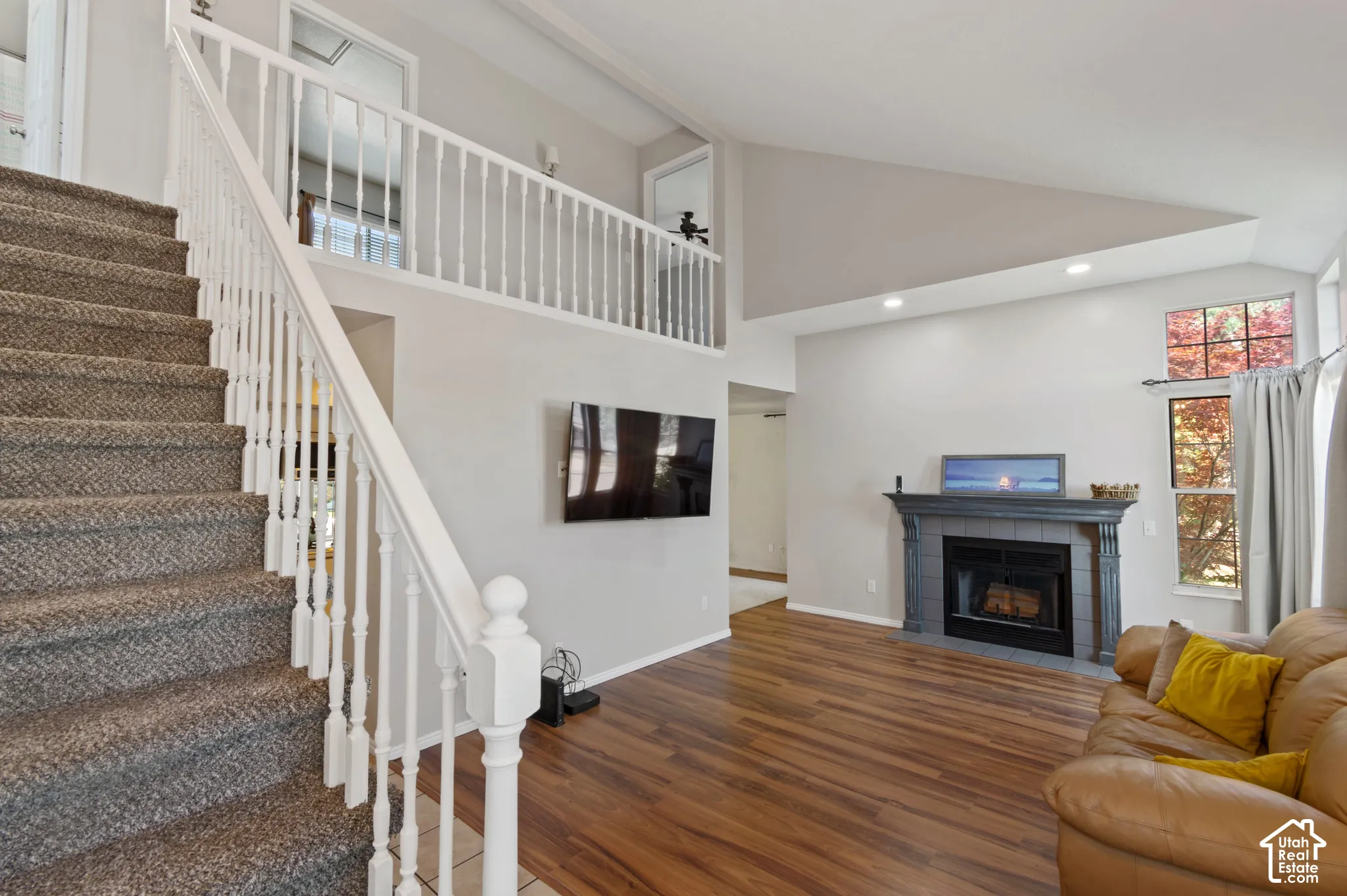 Living room with wood finished floors, a tile fireplace, recessed lighting, and high vaulted ceiling