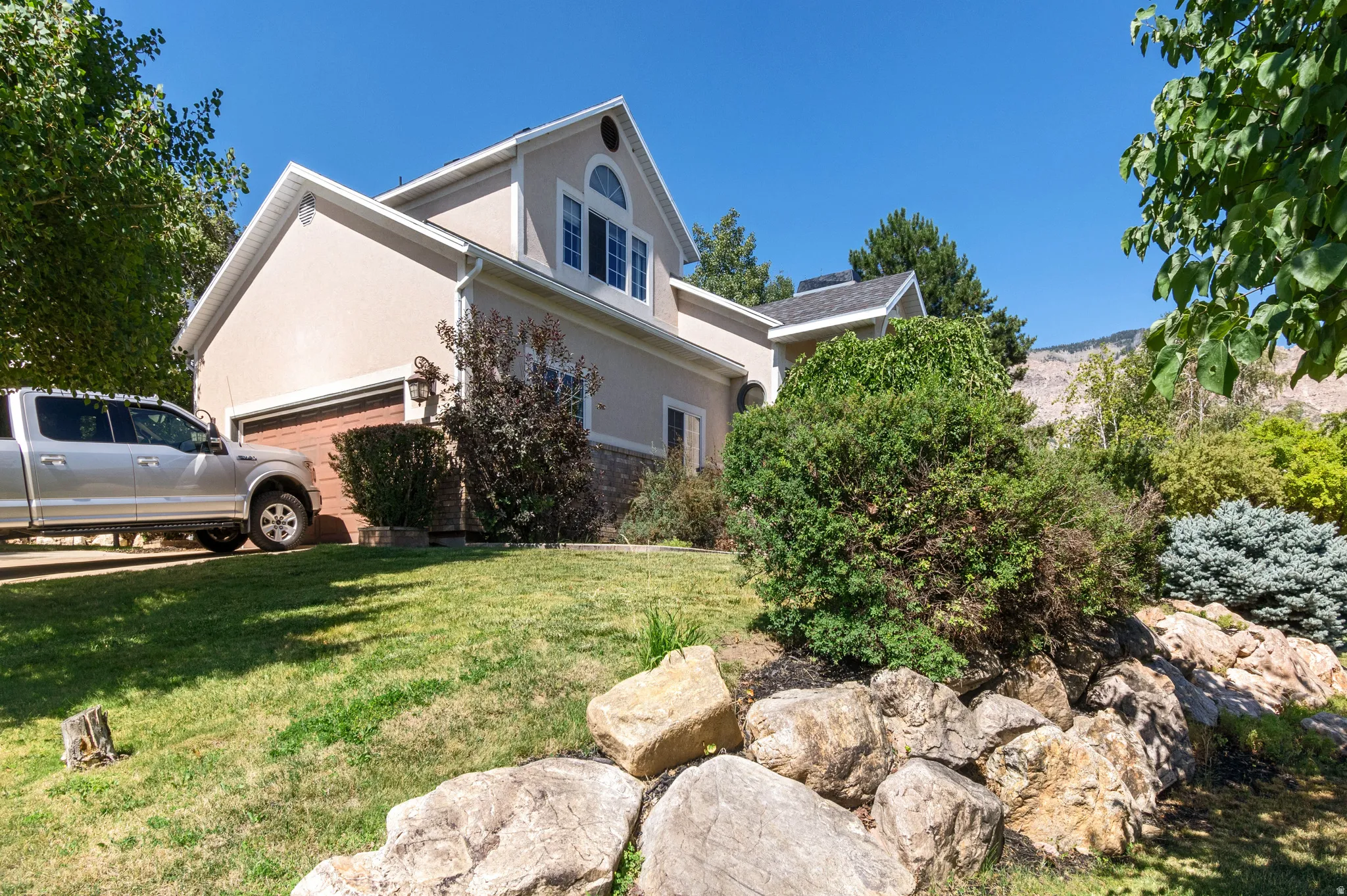 View of side of home with stucco siding, a lawn, and a garage