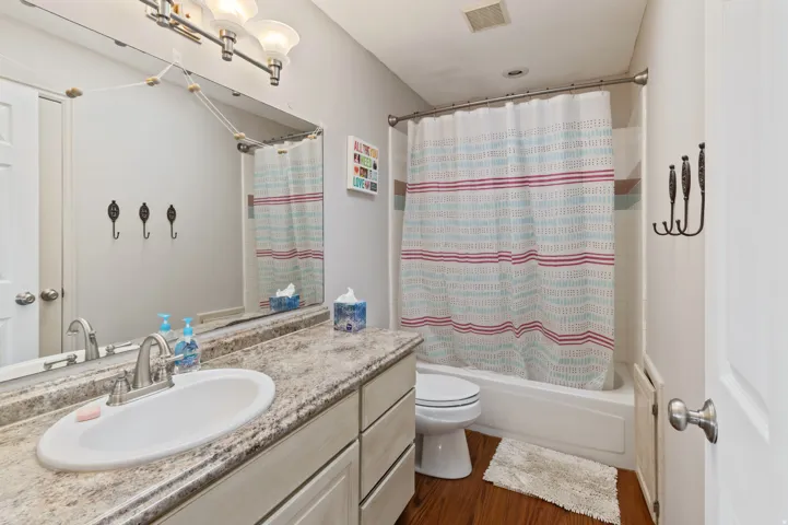 Bathroom featuring vanity, shower / tub combo, and dark wood finished floors