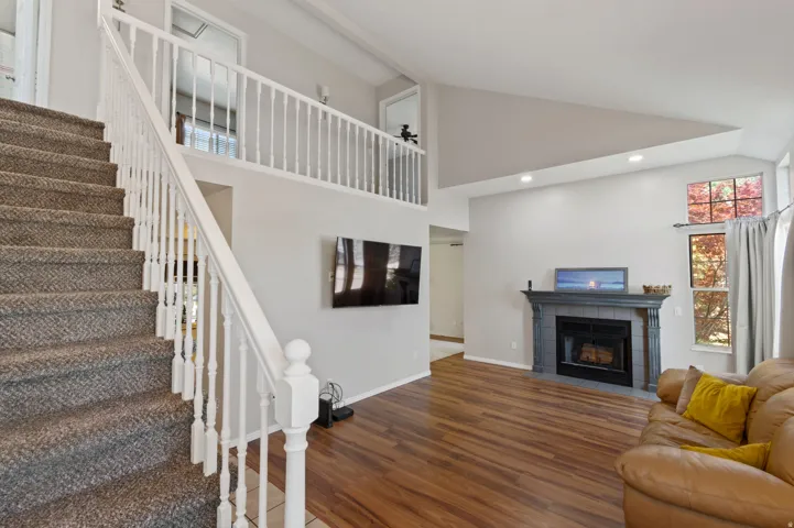 Living room with wood finished floors, a tile fireplace, recessed lighting, and high vaulted ceiling