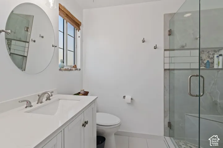 Full bath with a marble finish shower, vanity, and light tile patterned floors