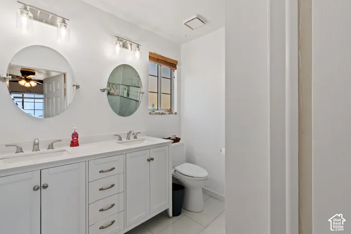 Bathroom featuring double vanity, a ceiling fan, and light tile patterned floors