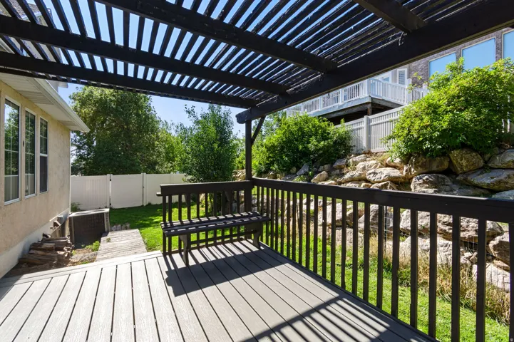 Deck with a fenced backyard, a pergola, and a gate