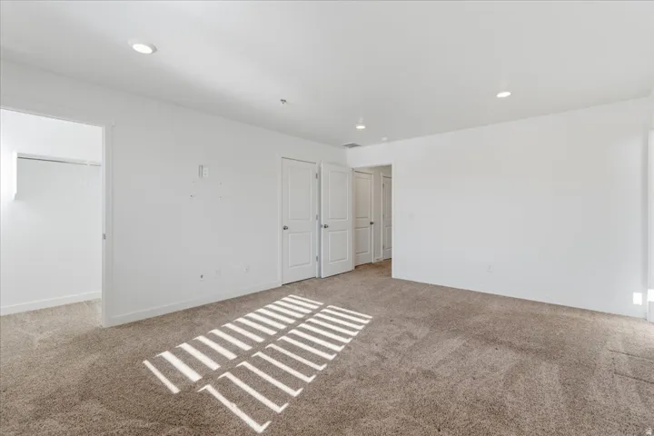 Bedroom featuring light carpet, recessed lighting, and a spacious closet