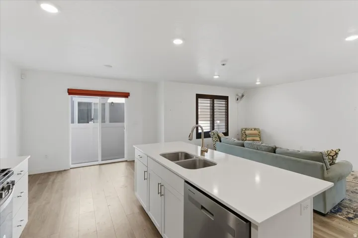 Kitchen featuring white cabinets, open floor plan, appliances with stainless steel finishes, light wood-type flooring, and recessed lighting